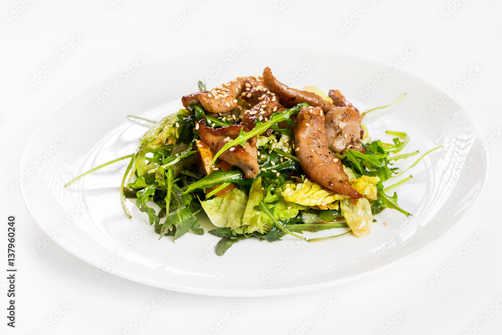 Closeup image of roasted duck at plate with green salad isolated at white background.