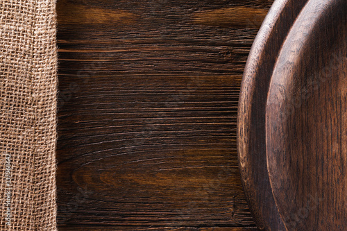 Closeup background of sack cloth and round tray at brown wooden board.