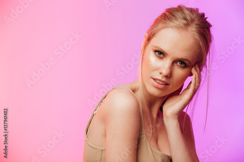 Beautiful woman standing and posing over pink background