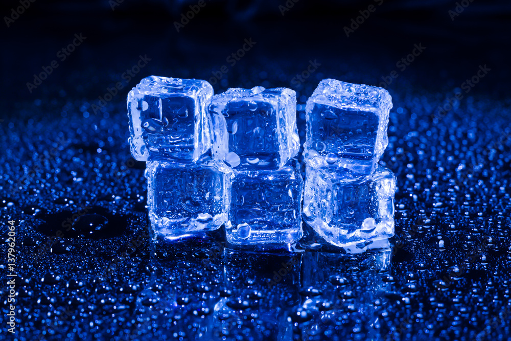 Ice cubes in blue light on black wet table. Ice cubes in blue light on black wet table.