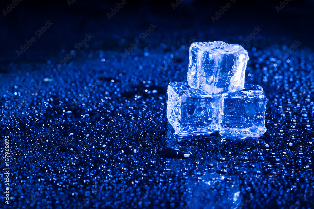 Ice cubes in blue light on black wet table. Ice cubes in blue light on black wet table.