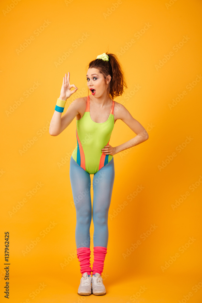 Happy young fitness woman posing over yellow background. Happy young fitness woman posing over yellow background.