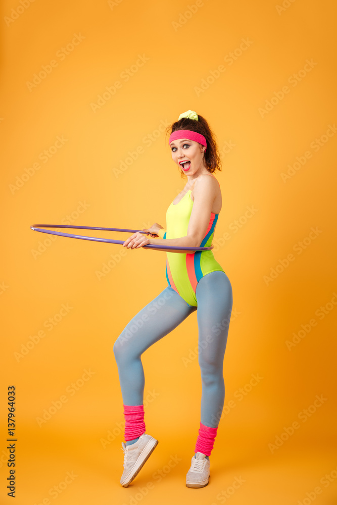 Cheerful young fitness woman working out and using hula hoop Cheerful young fitness woman working out and using hula hoop