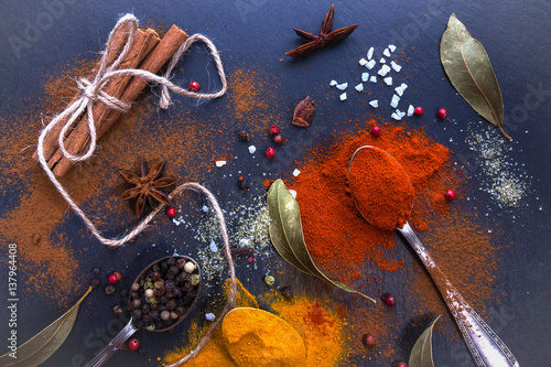 Different spices on a black background. Bay leaf, turmeric, paprika, star anise, cinnamon sticks, pepper. Top view