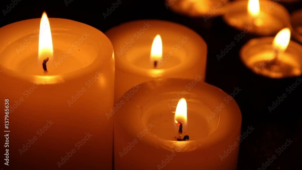 Candles burning at night on a wooden table. Small and big candles and bokeh lights background. Candles burning at night on a wooden table. Small and big candles and bokeh lights background.