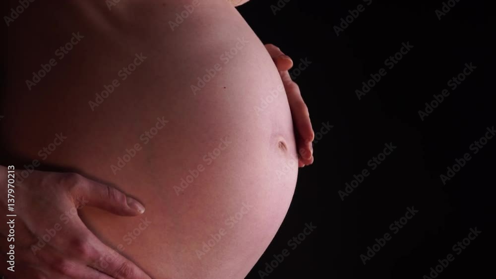 Pregnant woman no face touching caressing her naked big belly, closeup on black. Pregnancy, motherhood, baby anticipation and new life concept. 4K ProRes HQ codec Pregnant woman no face touching caressing her naked big belly, closeup on black. Pregnancy, motherhood, baby anticipation and new life concept. 4K ProRes HQ codec