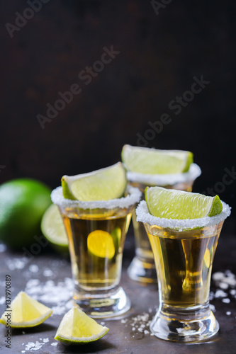 Golden mexican tequila shot with green lime and salt