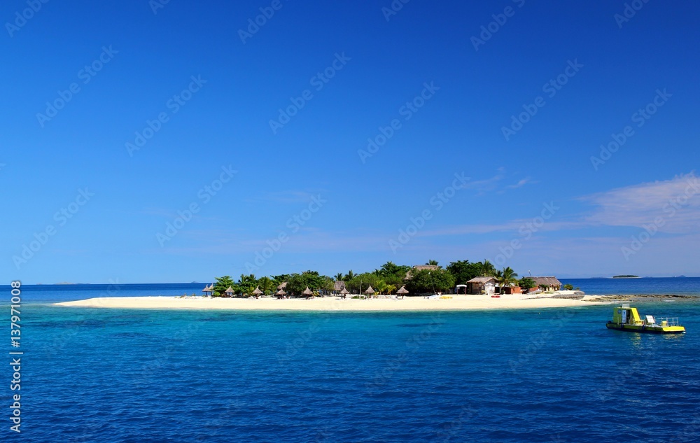 Winzige traumhafte Insel im Pazifik / Hütten und Boot / blaues Meer und klarer Himmel / Fiji