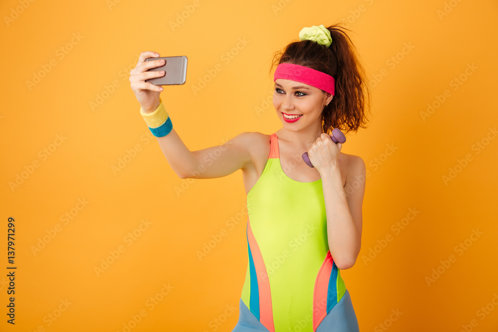 Smiling fitness woman with dumbbell making selfie using cell phone Smiling fitness woman with dumbbell making selfie using cell phone