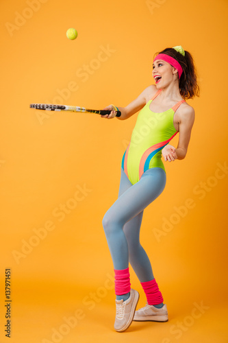 Happy joyful young sportswoman standing and playing tennis