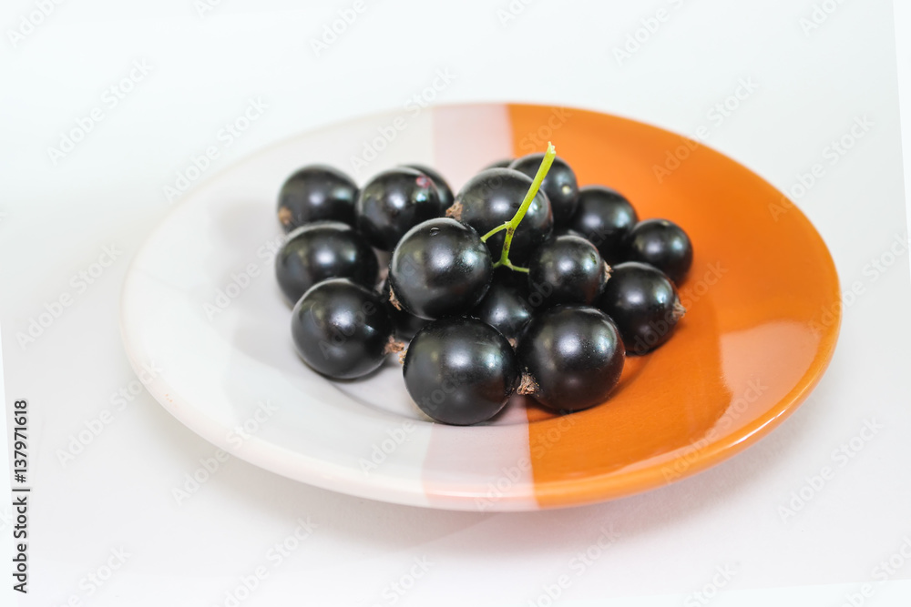 Large ripe berries of a black currant on a plate Large ripe berries of a black currant on a plate