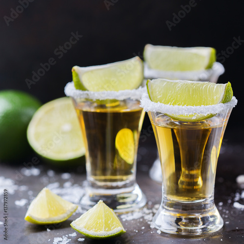 Golden mexican tequila shot with green lime and salt