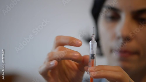 Female hand flicking air bubbles out of syringe