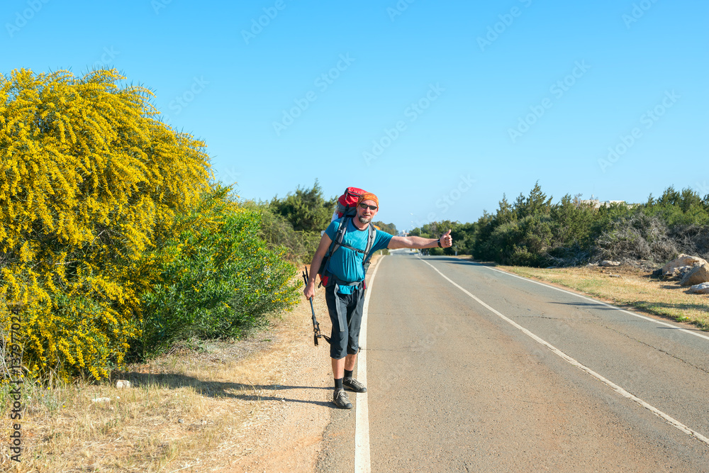 Fototapeta premium Bearded man with backpack is traveling hitchhiking