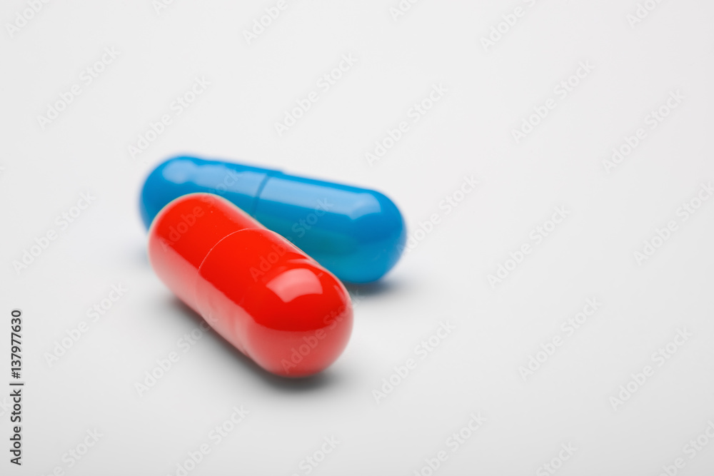 Two medical pills blue and red with shadows