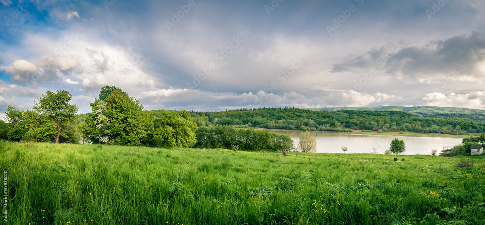 Beautiful landscape. The lake is between the green meadows and mountains.