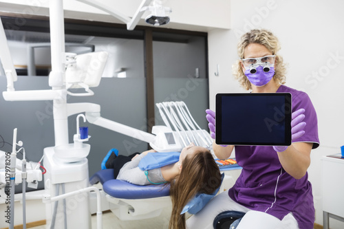 Dentist Showing Tablet Computer With Blank Screen By Patient