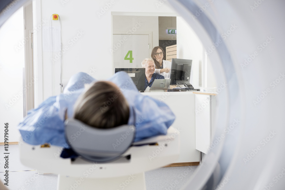 Doctor's Using Computers While Patient Undergoing CT Scan