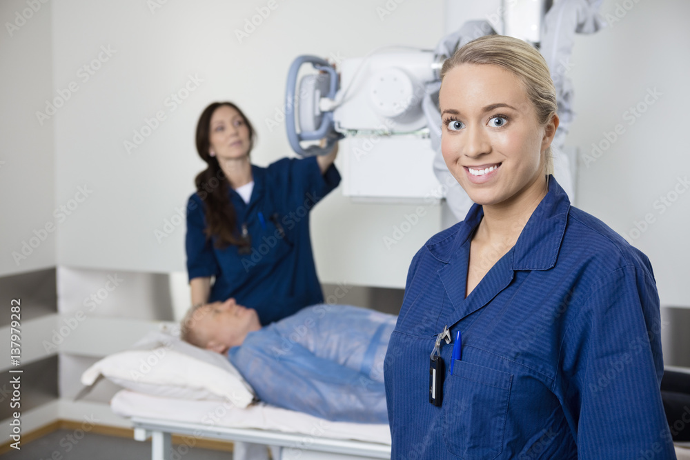 Fototapeta premium Young Radiologist Smiling While Colleague Taking Patient's Xray