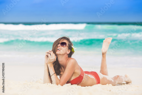 portrait of long haired woman in red bikini and sunglasses lying on tropical beach. La Digue, Seychelles