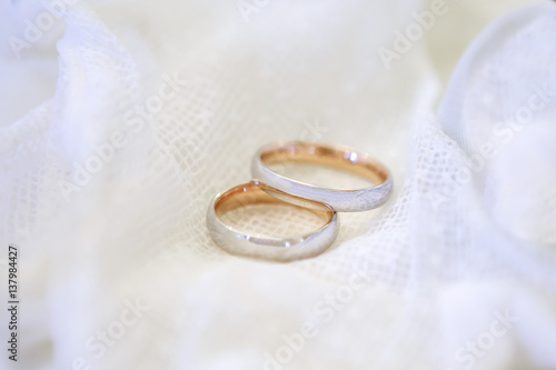 Two Golden wedding rings framed by white lace. A symbol of fidelity and marriage on a white background.