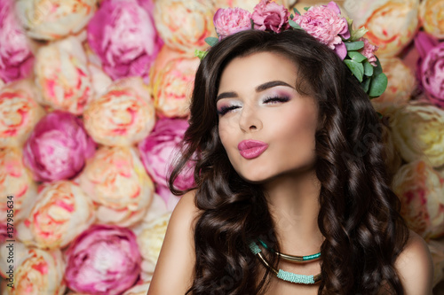 Beautiful Brunette Model Blowing a Kiss on Summer Flowers Background