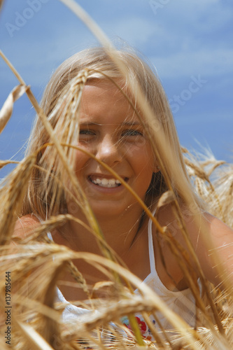 close-up of happy smiling blonde woman or teenage girl on cereal field (sunlight, nature, summer holiday, vacation and people concept)
