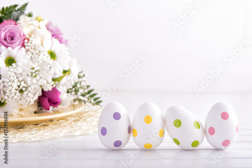 Branches of fresh mimosa with decorative easter eggs on wooden table