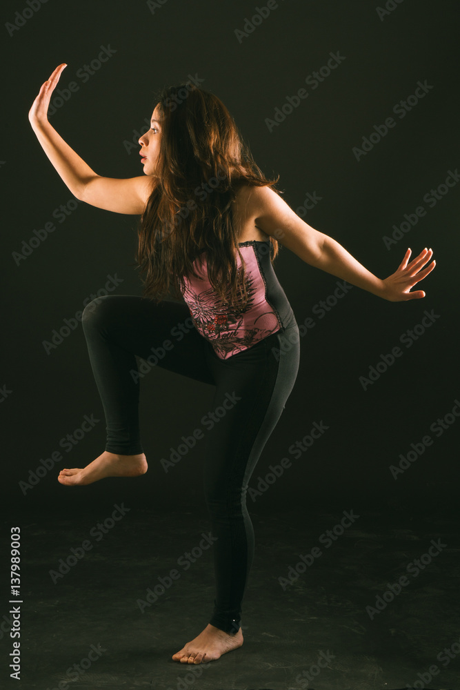 mujer joven latina realizando contorsiones, piruetas, gestos y acrobacias en un estudio con fondo negro y vestida con corsé