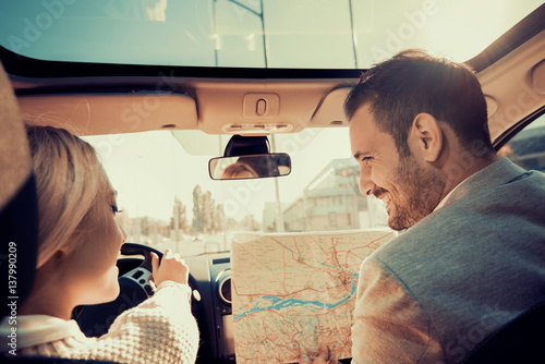 Smiling man and woman using map on roadtrip photo