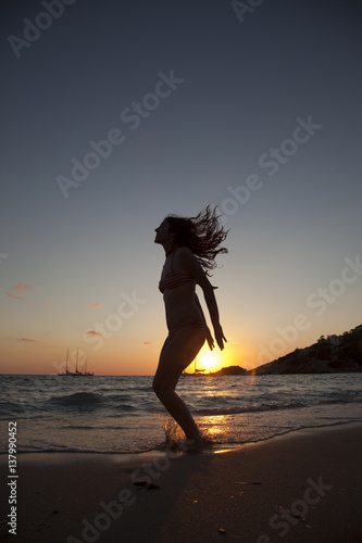 silhouette of a woman jumping isolated on a sunset beach