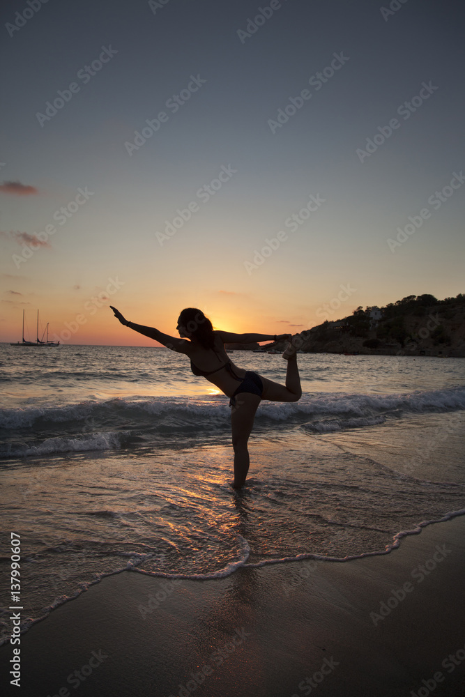 silhouette of a woman doing exercises isolated on a sunset beach