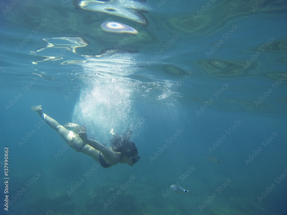 breathtaking turquoise sea with a young woman scuba diving isolated under the sea