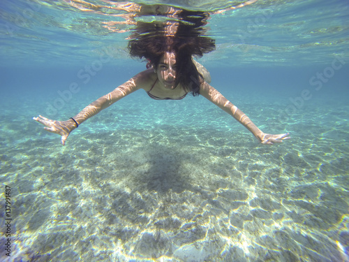 young woman submerged in the deep turquoise sea swimming