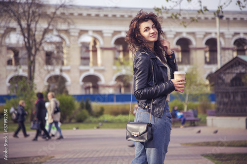 Brunette beautiful stylish caucasian woman in casual outfit on a walk on european city street drinking coffee. copy space © AnnaDemy