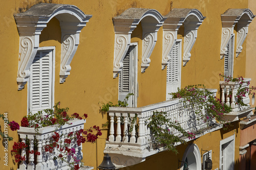 Bright yellow facade of a colonial style building covered in plants and flowers in the historic UNESCO World Heritage Site of Cartagena de Indias in Colombia photo