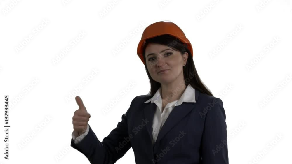 Business woman in safety helmet points to something behind her and turns to the camera with thumbs up approval gesture against white background. 4k footage PNG with alpha channel.