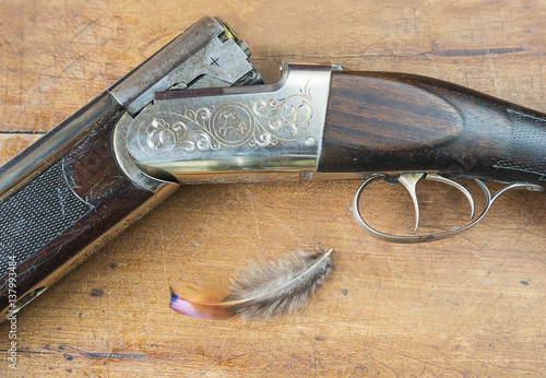 hunting rifle and pheasant feather on a whooden background photo