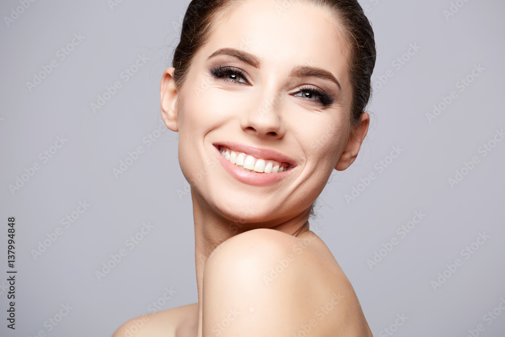 Pretty girl with smokey eye makeup, with naked shoulders, looking at camera and smiling, beauty photo, copy space, close up. Pretty girl with smokey eye makeup, with naked shoulders, looking at camera and smiling, beauty photo, copy space, close up.