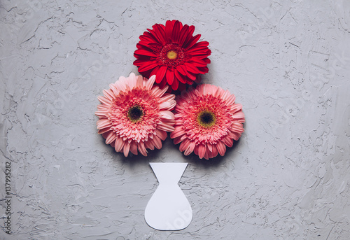 Creative Spring bouquet Gerbera flowers  on the table of the cement concrete texture with paper craft vase. March 8 concept. Design pattern photo