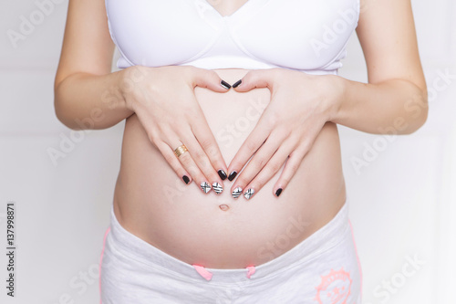 Wallpaper Mural Pregnant caucasian white woman standing in white bra and shorts, holding her belly. copy space Torontodigital.ca