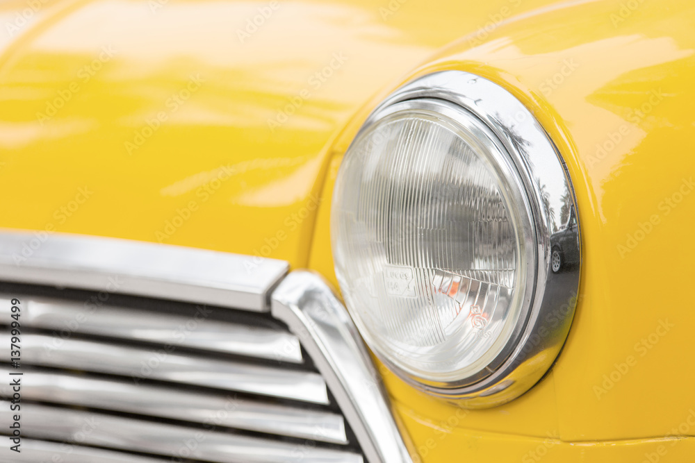 Headlight of old vehicle close up shot - car of Primrose Yellow color.