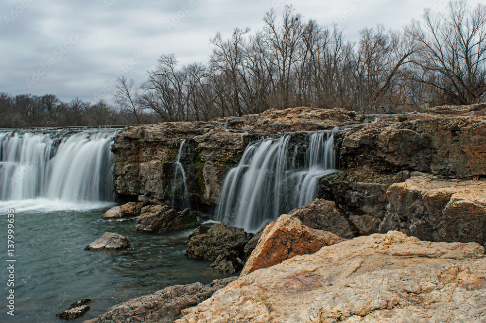 Fototapeta premium Waterfall among boulders on a warm winter day makes a scenic view