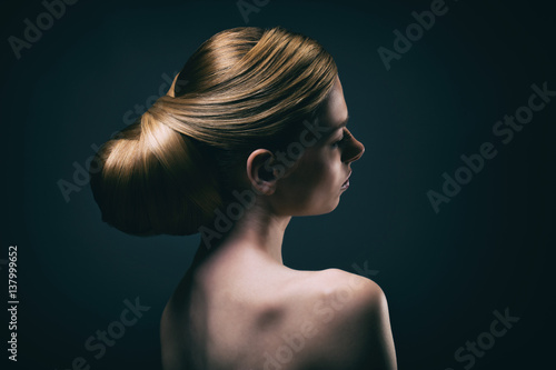 Portrait d'une jeune femme portant un chignon, de profil 