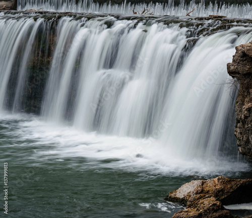 Waterfall among boulders on a warm winter day makes a scenic view.