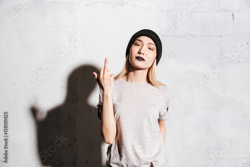Bilde på lerret Stylish woman with black lipstick standing and showing middle finger
