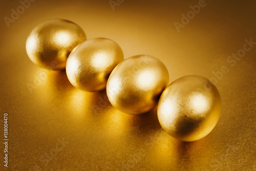 four gold Easter eggs on a shiny background