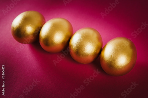 four gold Easter eggs on a purple background