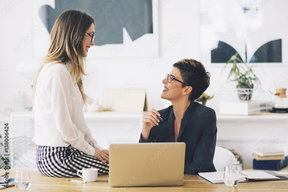 Happy businesswomen talking in the office Happy businesswomen talking in the office
