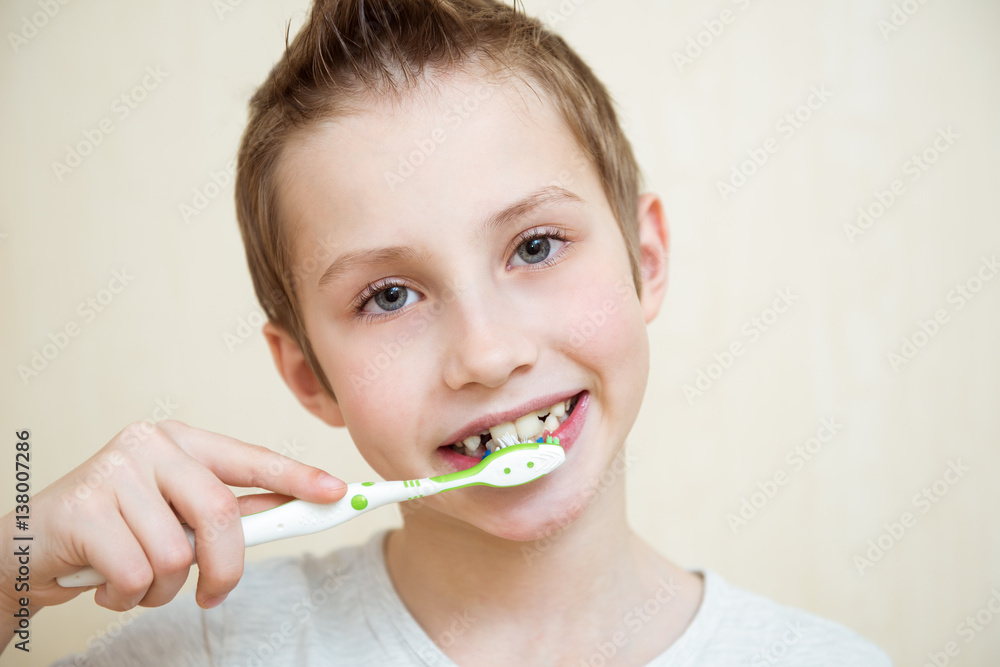 Cute boy brushing his teeth. Light background Cute boy brushing his teeth. Light background